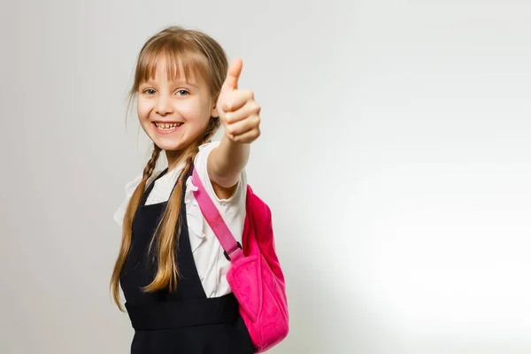 Carino sorridente studentessa in uniforme in piedi su sfondo bianco — Foto Stock