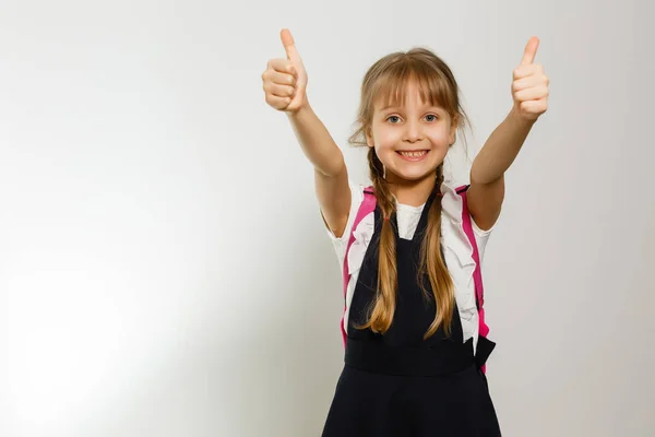 Carino sorridente studentessa in uniforme in piedi su sfondo bianco — Foto Stock