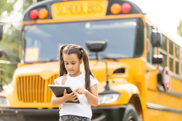 Roztomilé dívka s batohem stojící v blízkosti autobusu jít do školy pózování na kameru zamyšlený close-up — Stock fotografie