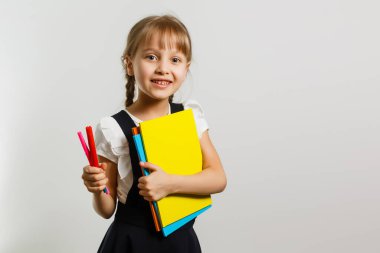 Sırt çantalı küçük sarışın kız portresi beyaz arka planda izole edilmiş.