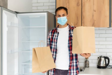 Paket teslimatçısı elinde yiyecek, koruyucu maskeli bir teslimatçı.