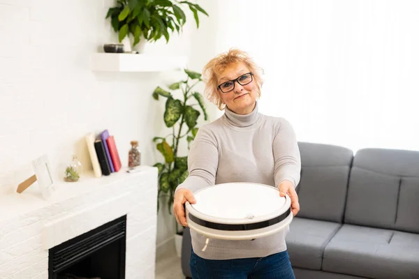 한연로 한 여자가 아파트에서 로봇 청소기를 사용하는 모습 — 스톡 사진