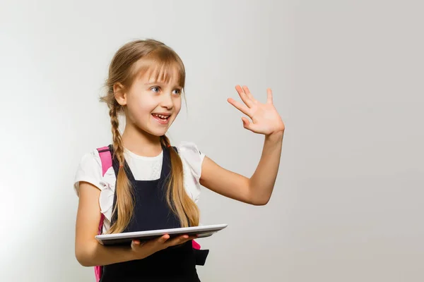 A menina usando o tablet no fundo da parede branca — Fotografia de Stock