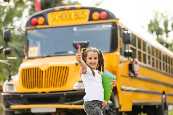 Linda chica con una mochila de pie cerca de autobús que va a la escuela posando a cámara pensativo primer plano — Foto de Stock