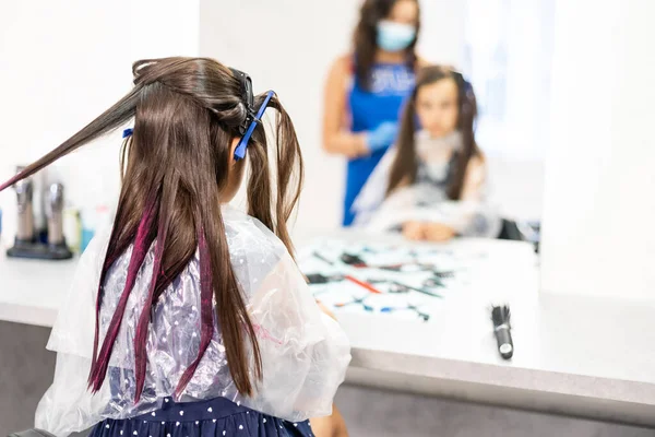 Friseur macht eine Frisur zu niedlichen kleinen Mädchen. — Stockfoto