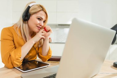Uzaktan kumanda evden çalışıyor. Laptop kullanan genç bir kadın. Mutfak ofisinde serbest çalışan bir işyeri. Tecrit edilmiş telgraf, kadın işi, internetten alışveriş. Uzaktan öğrenme öğrencisi. Yaşam tarzı anı.