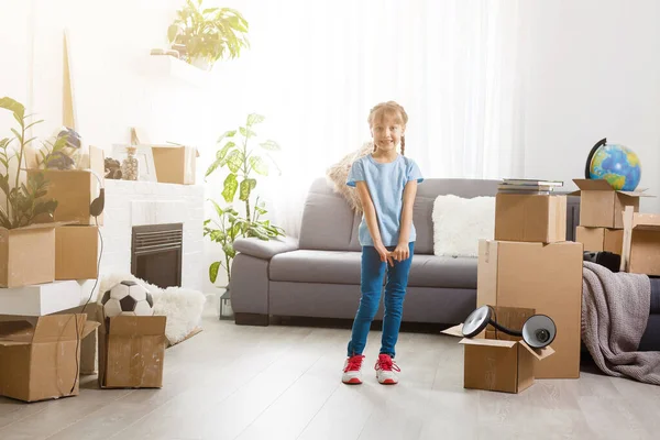 Klein meisje verhuist naar nieuw huis, vlakbij kartonnen doos. — Stockfoto