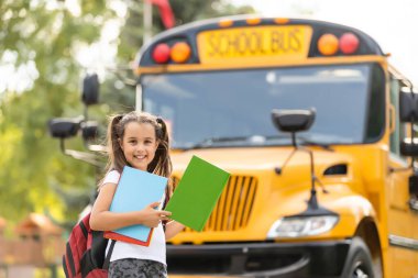 Sarı okul otobüsünün yanında sırt çantalı bir kız. Öğrenciler için taşıma