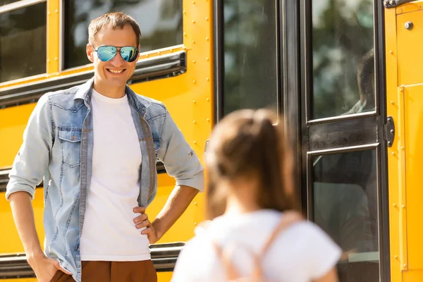Водитель школьного автобуса стоит перед автобусом — стоковое фото