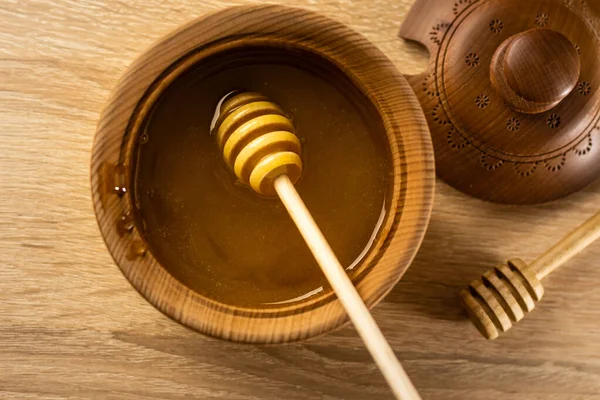 Miel en un recipiente de madera profunda, plato de madera rústica. La cuchara de madera gotea lentamente. —  Fotos de Stock