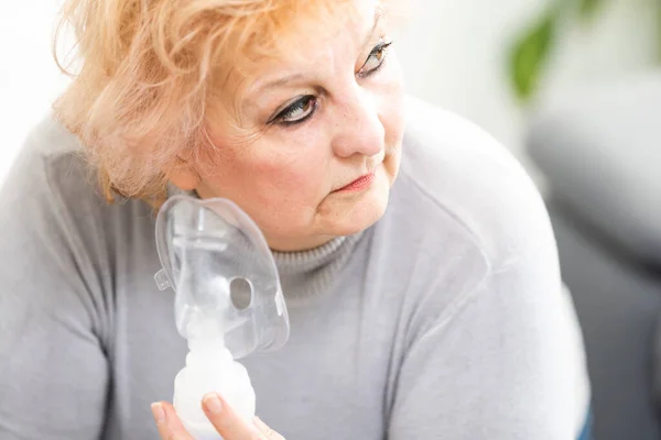 Donna anziana che utilizza macchina asma su sfondo chiaro — Foto Stock