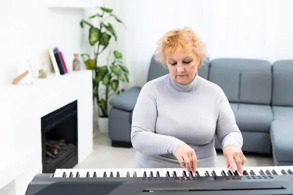 Snygg vuxen kvinna spelar synthesizer — Stockfoto