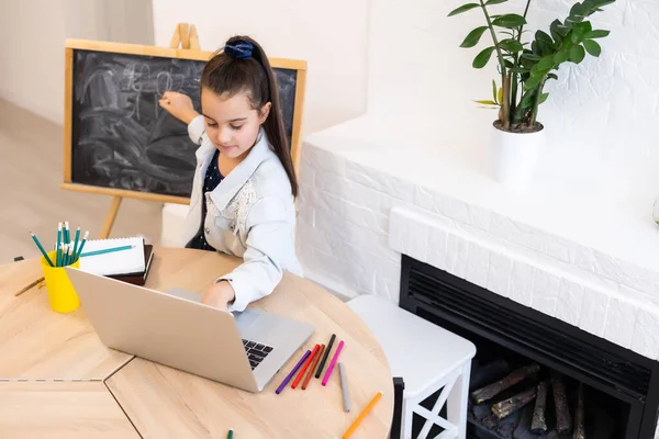 Menina da escola escrevendo cartas no quadro negro. Menina criança segurando giz e desenho em casa, educação distante — Fotografia de Stock