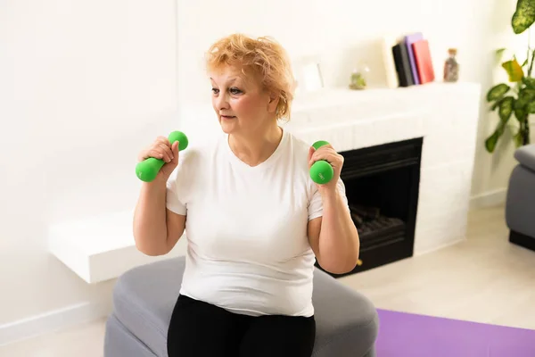Starší žena dělá fyzická cvičení s činkou — Stock fotografie