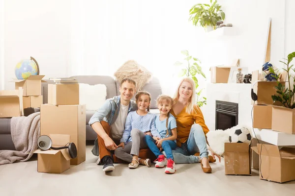 Familia feliz con cajas de cartón en casa nueva en el día de mudanza. —  Fotos de Stock