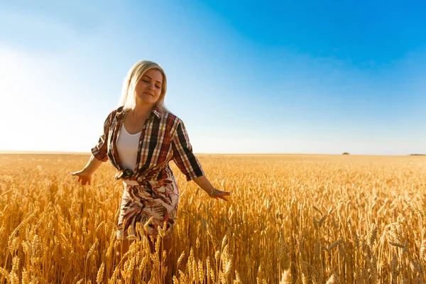 Mulher em um campo de trigo no fundo do sol poente — Fotografia de Stock