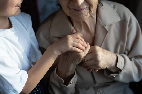 Unrecognizable grandmother and her granddaughter holding hands. — Stock Photo, Image