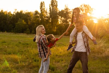 Mutlu aile: anne baba ve kız gün batımında doğada
