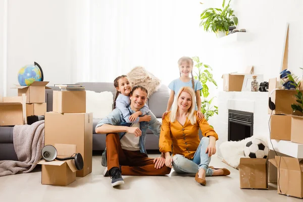 Famille heureuse avec des boîtes en carton dans une maison neuve au jour du déménagement. — Photo