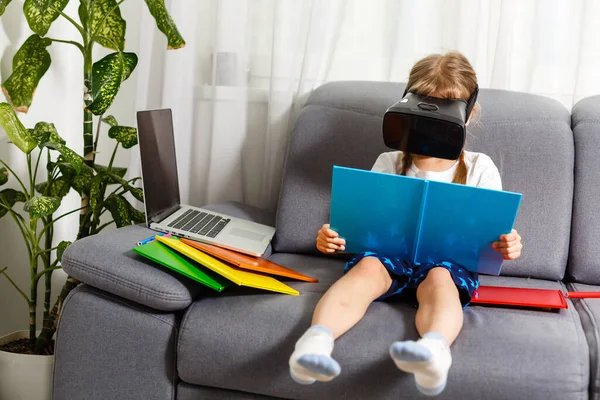 Sto provando le nuove tecnologie. Piccola scolaretta con grandi occhiali VR essere impressionato giocare giochi virtuali. Home school, educazione online, educazione a casa, concetto di quarantena - Immagine — Foto Stock