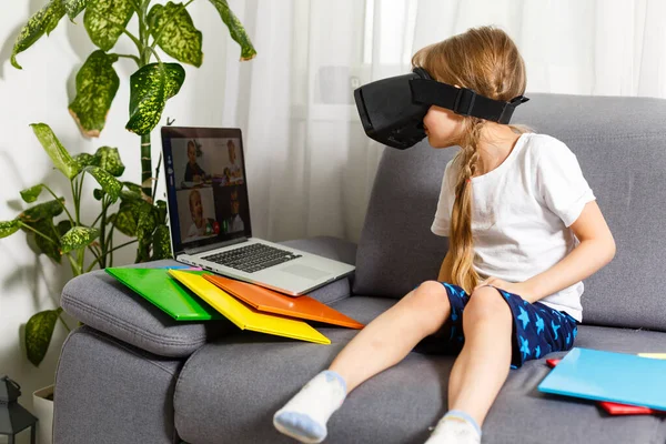 Trying new technologies. Little schoolgirl wearing big VR glasses being impressed playing virtual games. Home school, online education, home education, quarantine concept - Image