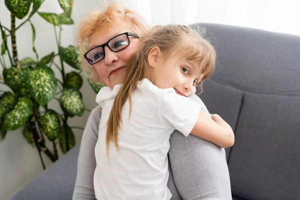 Happy senior woman hugging her beautiful grandchild - in kitchen at home — Stock Photo, Image