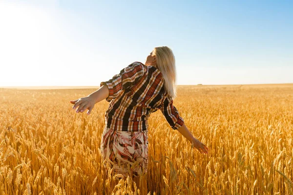 Mulher em um campo de trigo no fundo do sol poente — Fotografia de Stock