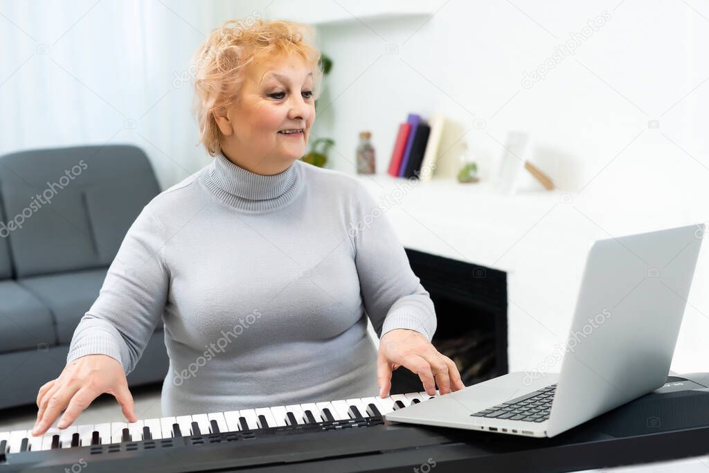 elderly woman learning to play synthesizer on laptop online at home