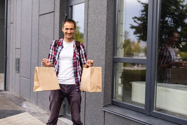 Lieferung, Post und Menschen-Konzept - glücklicher Mann, der Lebensmittel in Einweg-Papiertüten nach Hause bringt — Stockfoto