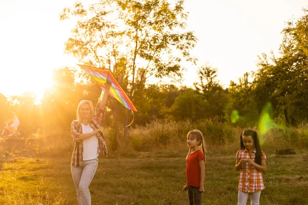 Feliz familia madre e hijos corren en el prado con una cometa en el verano en la naturaleza — Foto de Stock