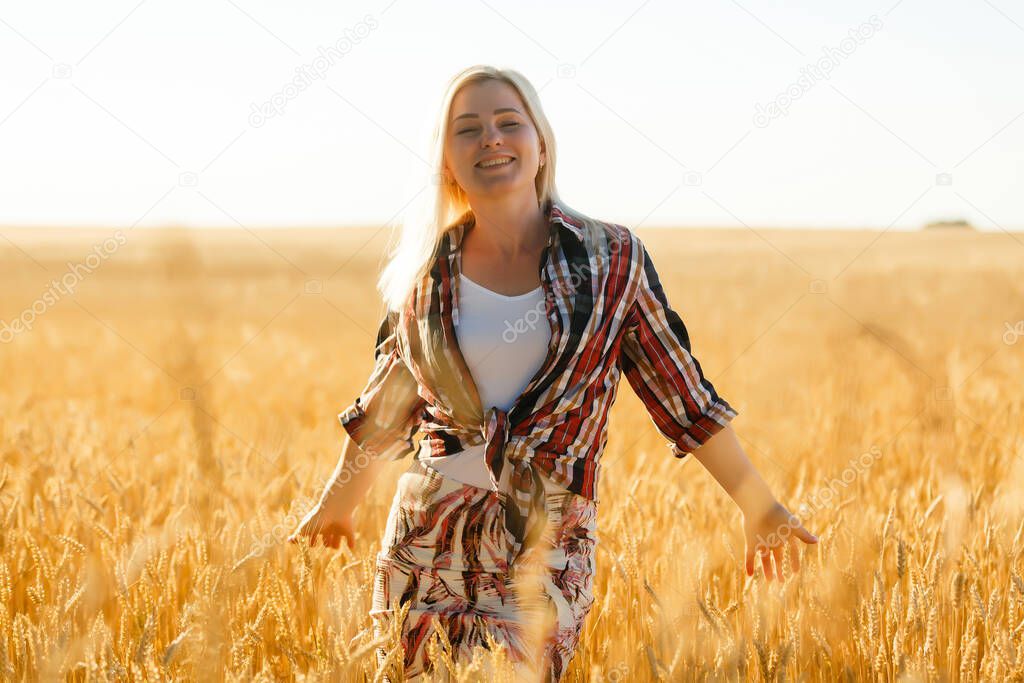 Woman in a wheat field on the background of the setting sun