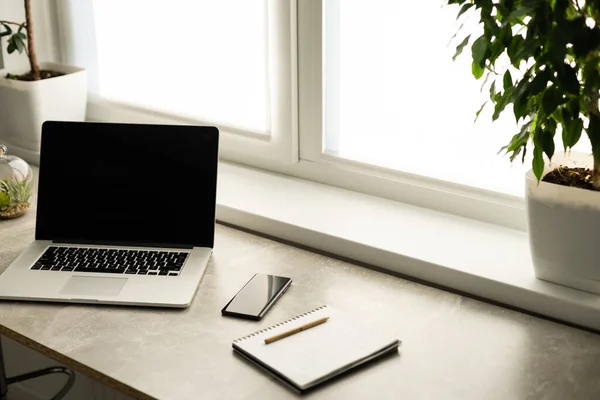 Vista de natureza morta de quarto de escritório com computador portátil aberto na mesa com reflexões pela janela brilhante, interior de escritório. Tecnologia profissional do local de trabalho em ambientes fechados. — Fotografia de Stock