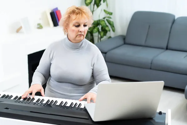 Senior vuxen kvinna i aktiv pensionering bor spelar piano i sitt hem. — Stockfoto
