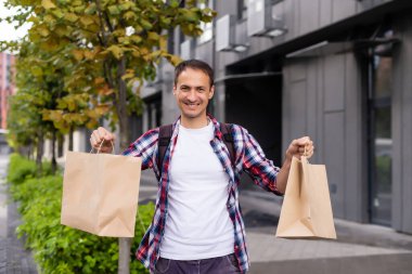 dağıtım, posta ve insan konsepti - tek kullanımlık kağıt torba içinde müşteriye yemek getiren mutlu bir adam