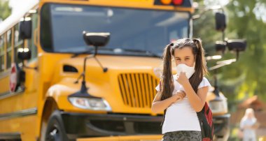 Coronavirus COVID-19 kavramı. Grip virüsünden korunmak için sağlık maskesi takan kız öğrenci. Sırt çantalı ve kitaplı öğrenci kız. Açık hava portresi. Çocuk okula geri döndü..