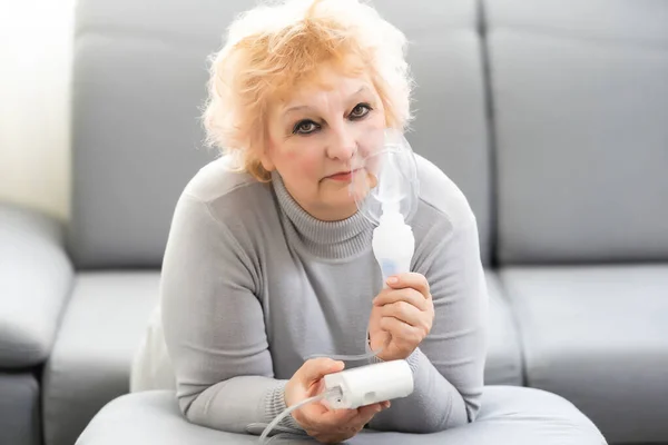 Donna anziana che utilizza macchina asma su sfondo chiaro — Foto Stock