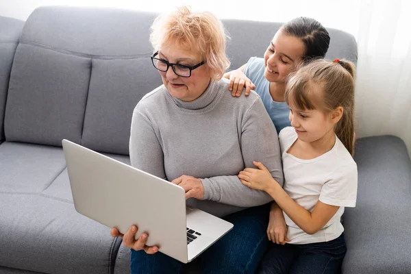 Nonna e due nipoti usano il computer portatile a casa — Foto Stock