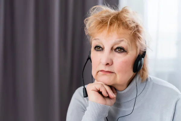 Посміхаючись сучасною зрілою жінкою 60-х років, Кавказька жінка в навушниках дивиться вебінарний онлайн вдома. Щаслива сірувата жінка добре вчиться в інтернеті. Технологія похилого віку — стокове фото