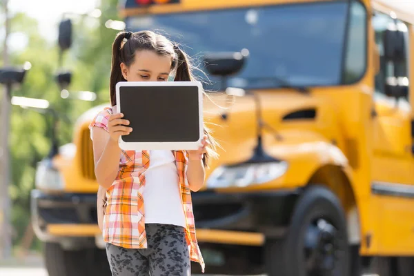 Rozkošná malá školačka v blízkosti školní autobus a při pohledu na kameru — Stock fotografie