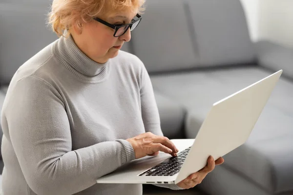 Sorridente anziana donna anziana con laptop a casa — Foto Stock