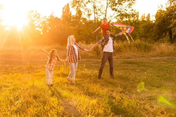 Щаслива сім'я, що йде в полі і дивиться на захід сонця — стокове фото