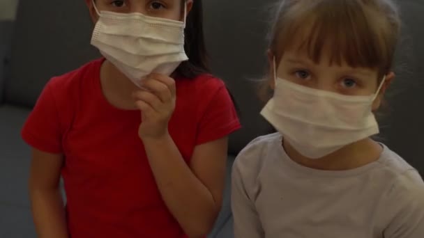 Zwei kleine Mädchen. Epidemischer pandemischer Coronavirus 2019-ncov sars covid-19 flu virus concept. Zeigefinger auf sterile Gesichtsmaske zeigen — Stockvideo