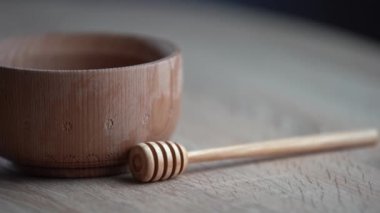 Koyu ahşap bir kasede bal, kırsal ahşap bir tabak. Tahta kaşık yavaşça damlıyor..