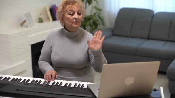 Oudere vrouw leren synthesizer spelen op laptop online thuis — Stockvideo