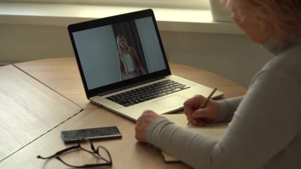 Close up wrinkled male hands writing information. Old mature woman working at office, using computer — Stock Video