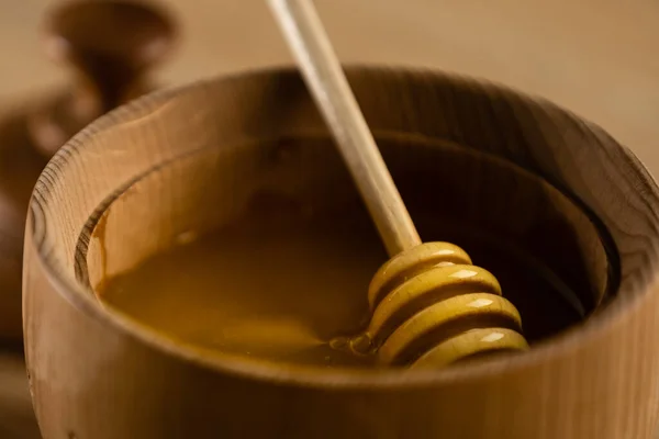 Miel goteando del tarro de miel en un tazón de madera. Primer plano. Sano orgánico. Miel gruesa que se sumerge de la cuchara de miel de madera, primer plano —  Fotos de Stock