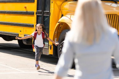 Annem okula at kuyruklu ve sırt çantalı kıza eşlik ediyor..