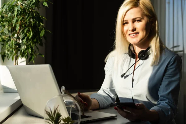 Portret van een serieuze casual zakenvrouw zittend aan tafel met laptop op kantoor en kijkend naar camera — Stockfoto