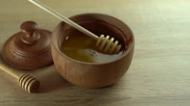 Bal damlıyor, ahşap kaseye bal damlatıyor. Yakın plan. Ahşap bal kaşığından batırılan sağlıklı organik bal, yakın plan. 4K UHD video görüntüleri. Yavaş çekim
