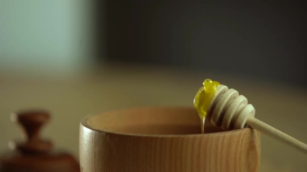 Miel con tarro de miel de madera en cuenco de madera sobre mesa de madera — Vídeos de Stock